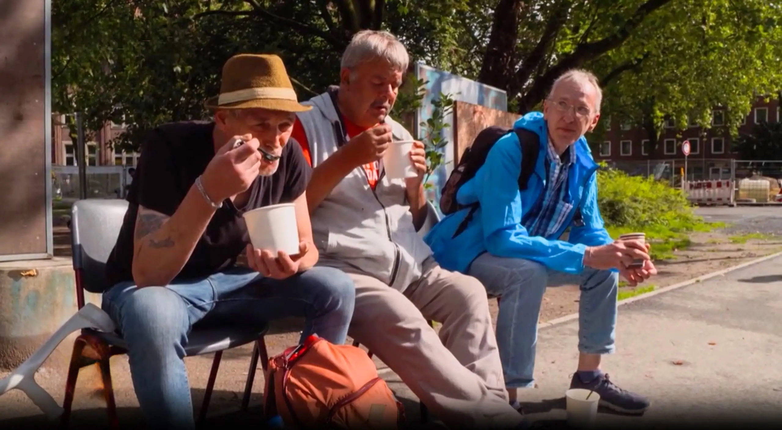 Drei Männer essen Suppe am Bremer Platz in Münster